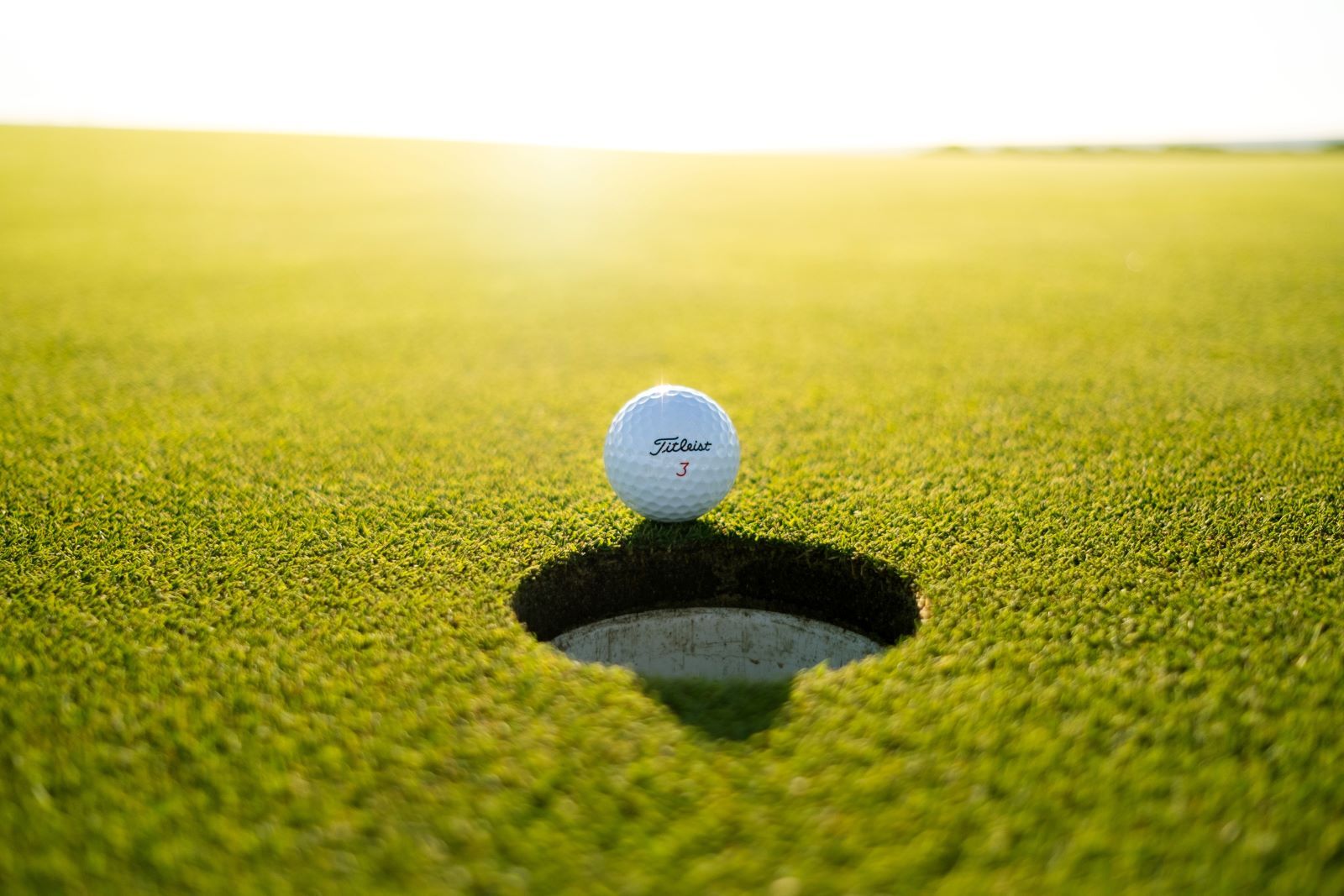 close-up shot of golf ball right beside a hole on golf course